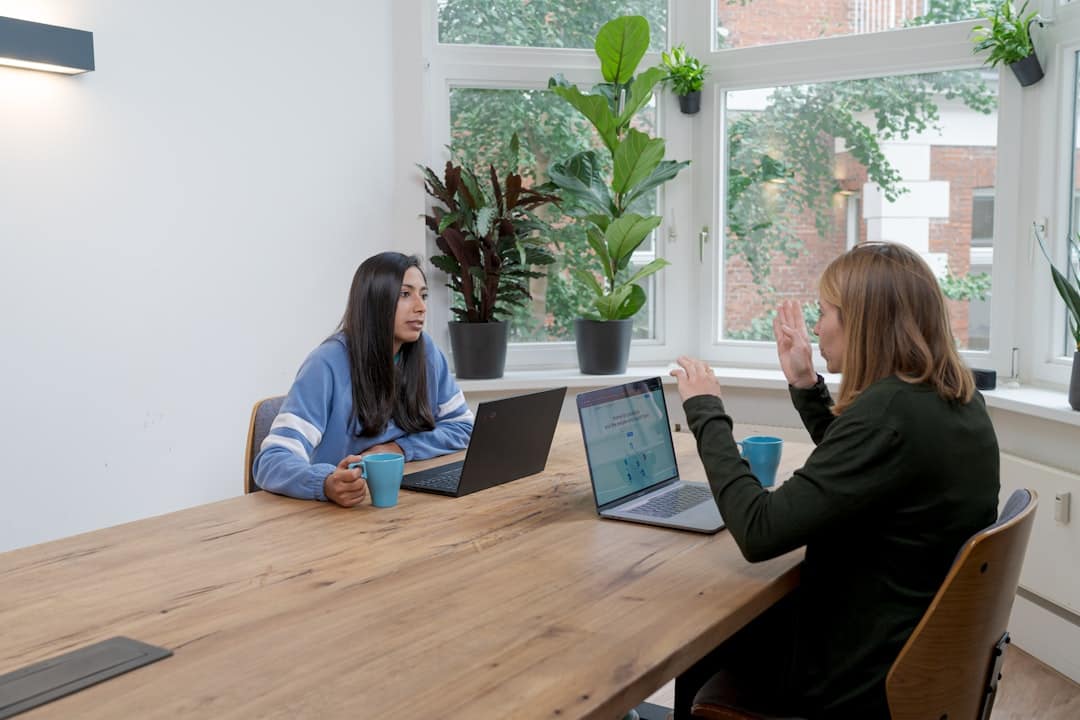 Photo by airfocus woman in blue long sleeve shirt sitting beside woman in black long sleeve shirt
